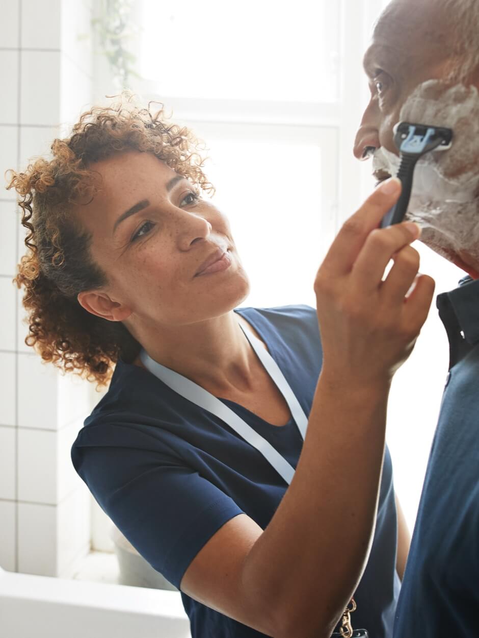 home care nurse helping elderly man shave