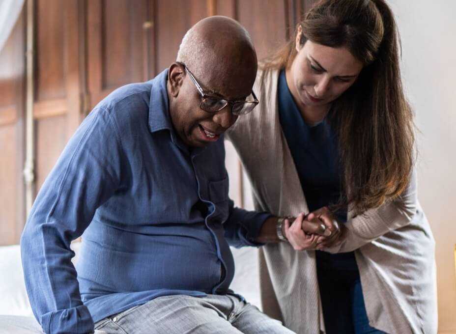 home care doctor helping patient get out of bed