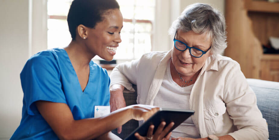 nurse and patient looking at computer tablet in home